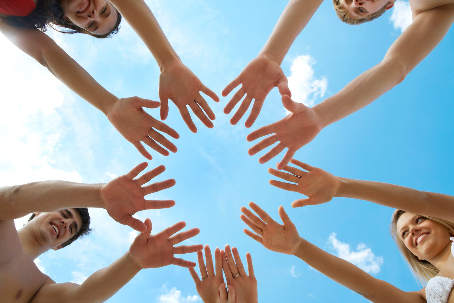 Circle of people's hands on a blue sky background
