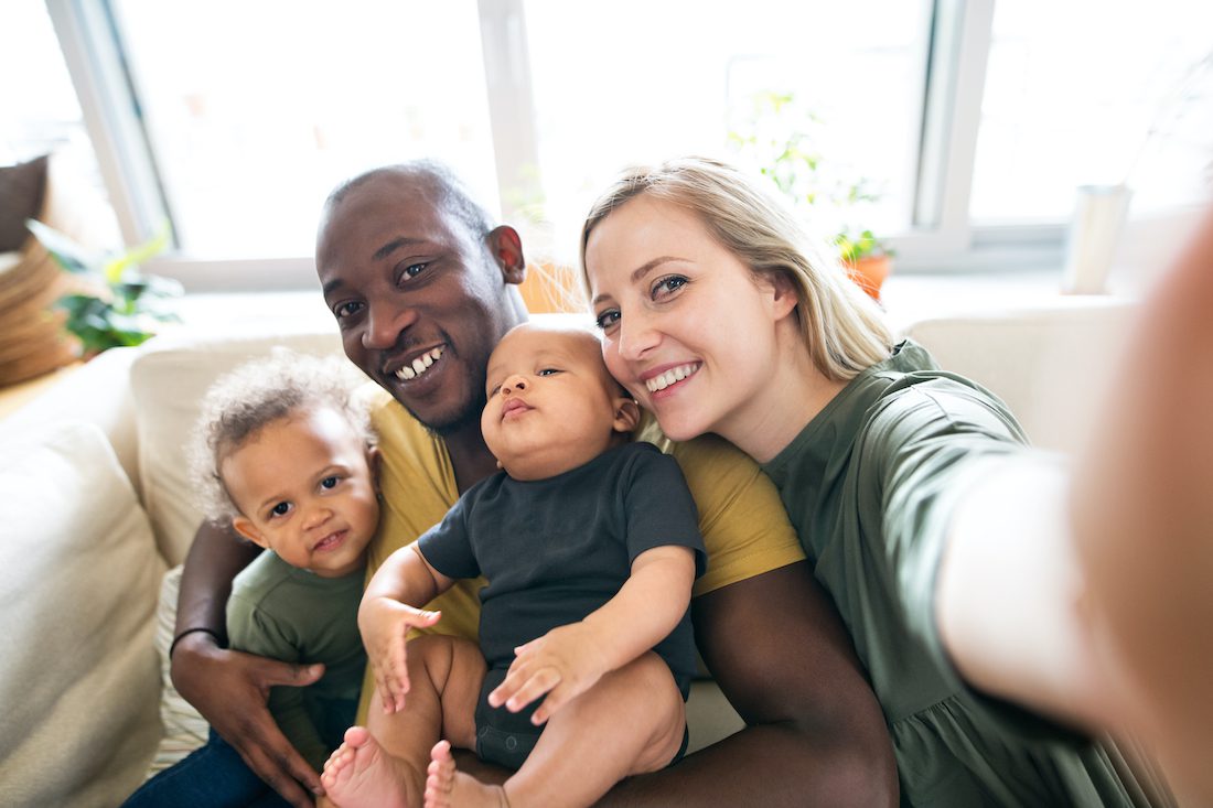 Young interracial family with little children taking selfie.