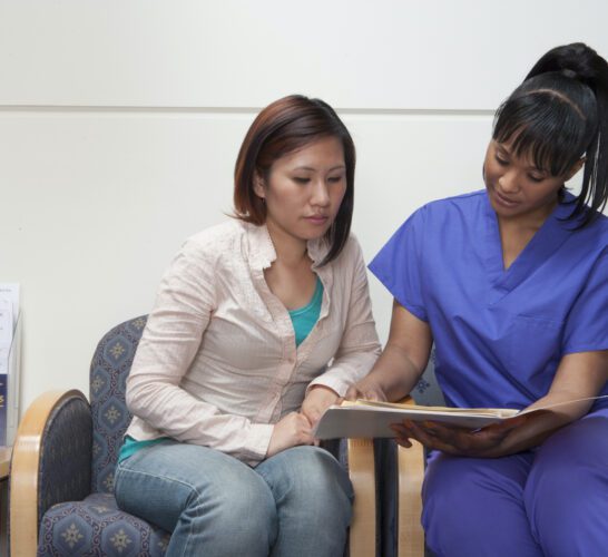 Patient in a medical setting sitting with a nurse.