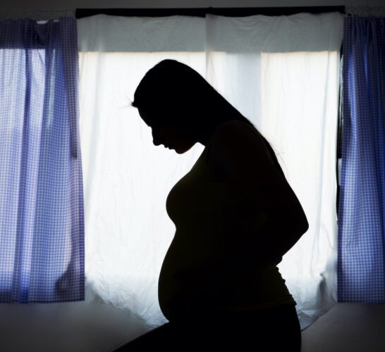 Silhouette of pregnant woman in her bedroom.